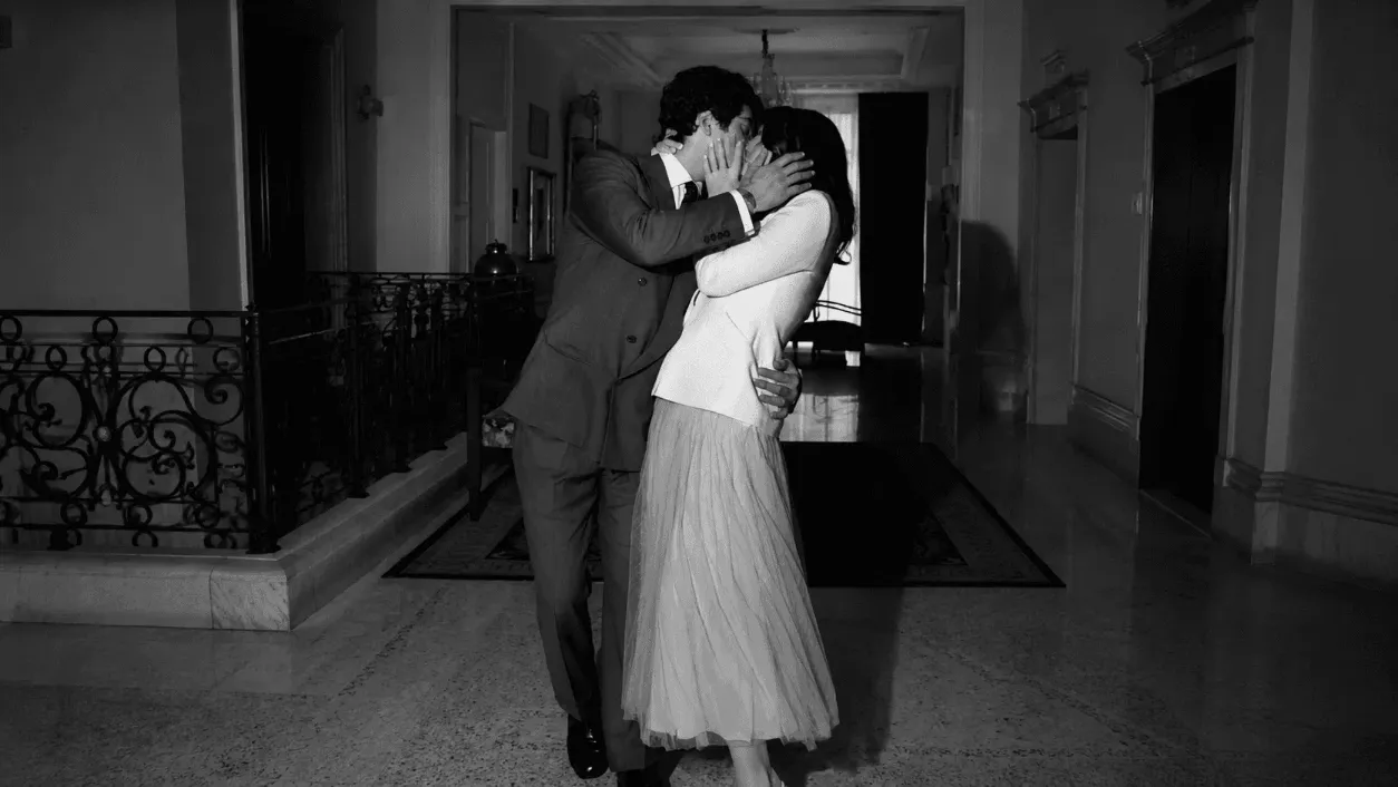 A couple dances closely in a dimly lit room, creating an intimate and nostalgic atmosphere in black and white.