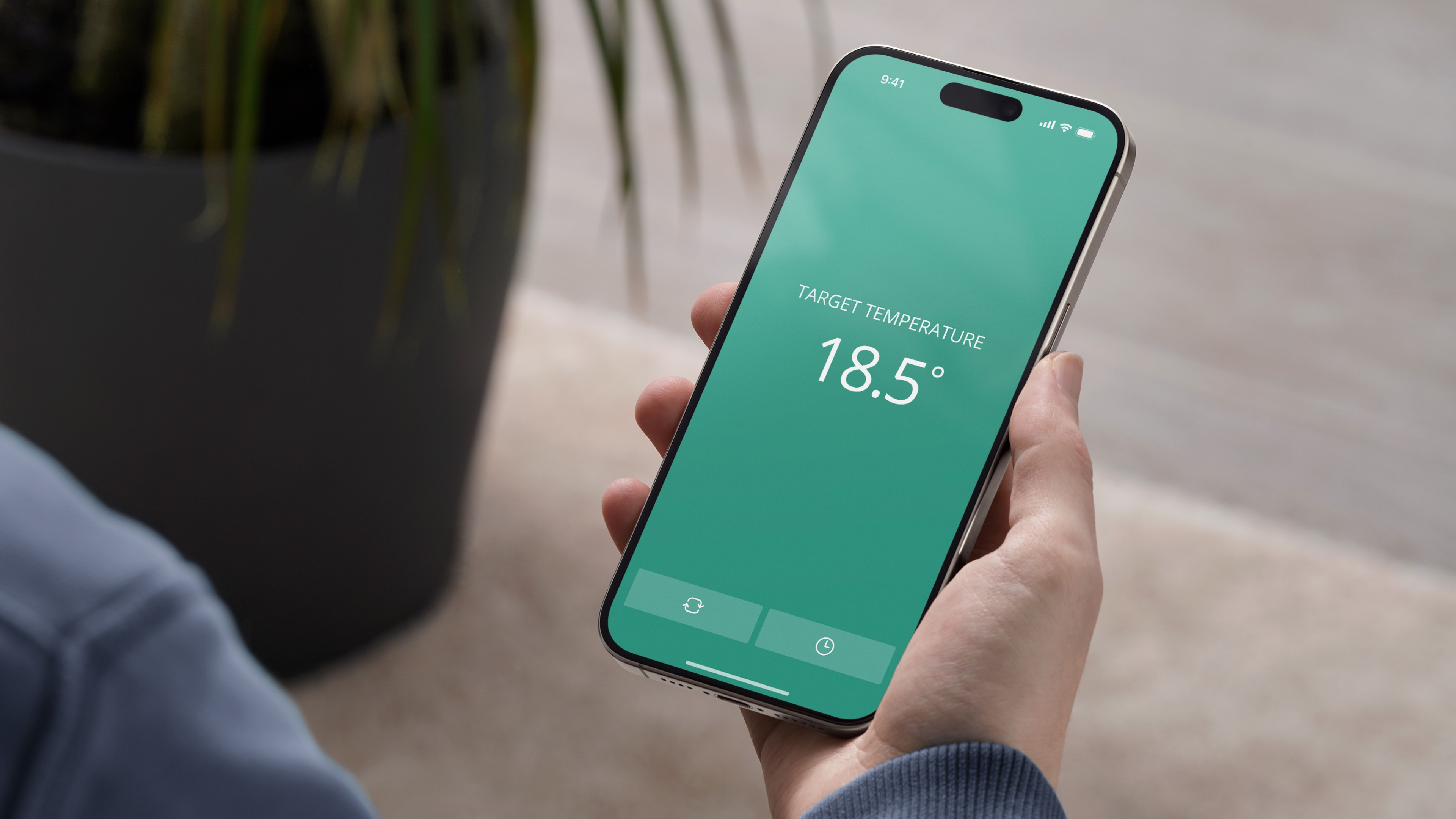 Hand holding smartphone displaying Honeywell smart thermostat interface with target temperature set to 18.5°C