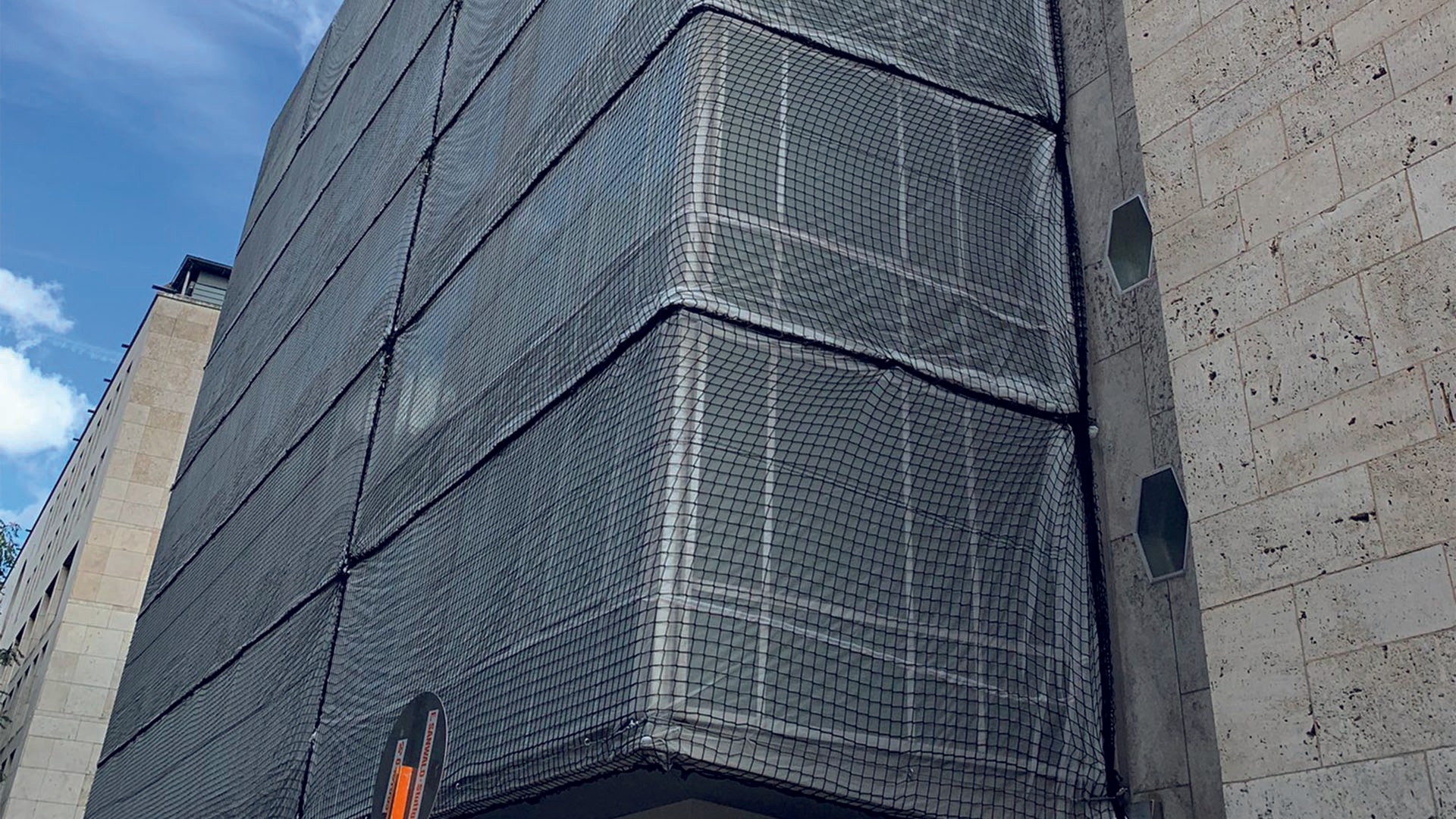 Smiling man in a maroon sweater working at a computer in a modern, industrial-looking lab or tech workspace.