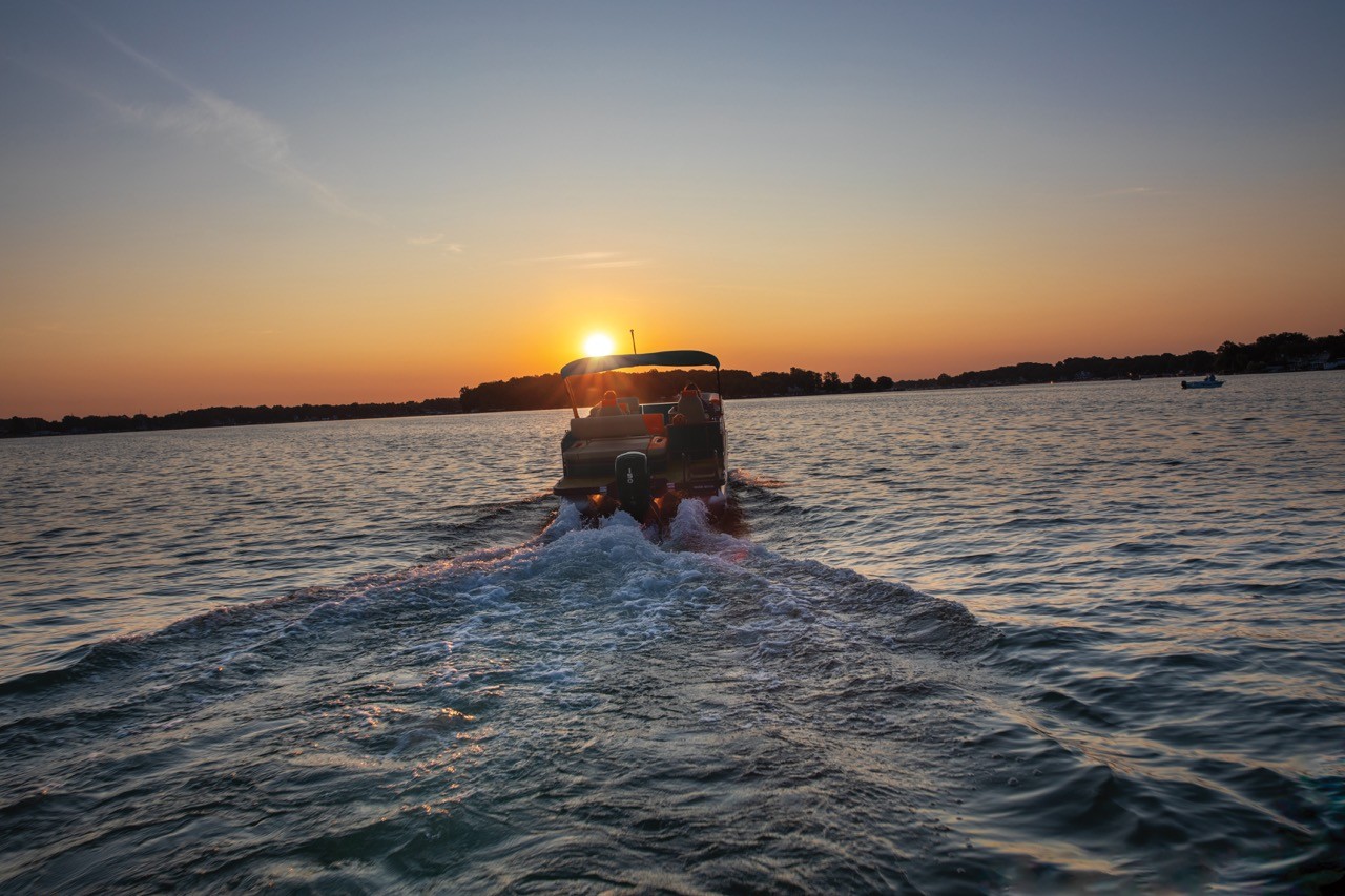 A pontoon cruising away on a lake