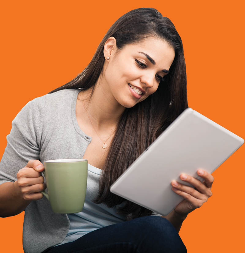 Adult learner sitting and reading from a tablet while holding a coffee mug, against an orange background