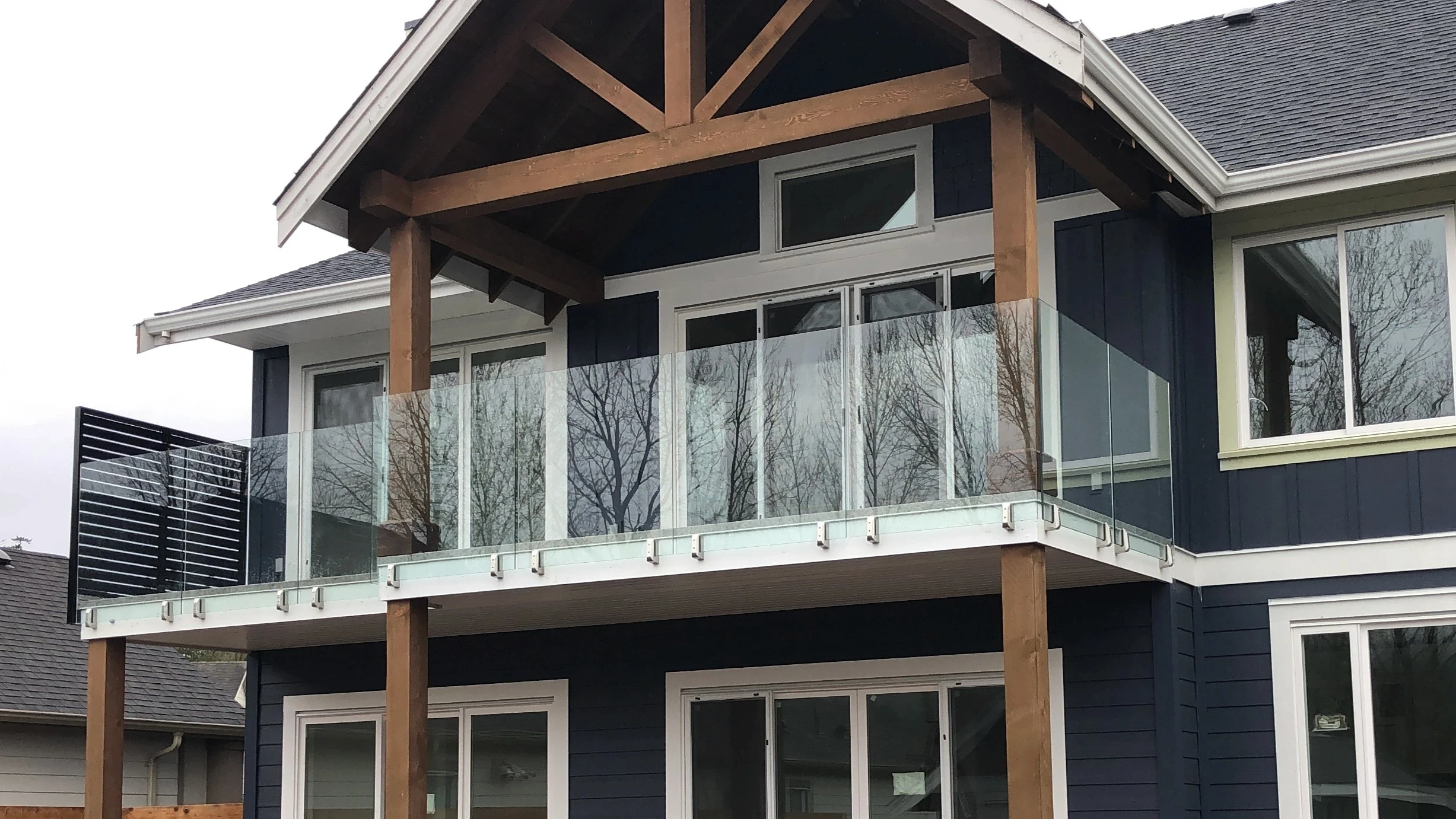 Spigot glass railing along a covered balcony with fascia mounted spigots and a horizontal slat privacy screen at the end.
