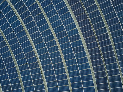 Close-up view of a patterned solar panel with alternating dark and light blue sections arranged in curved lines.