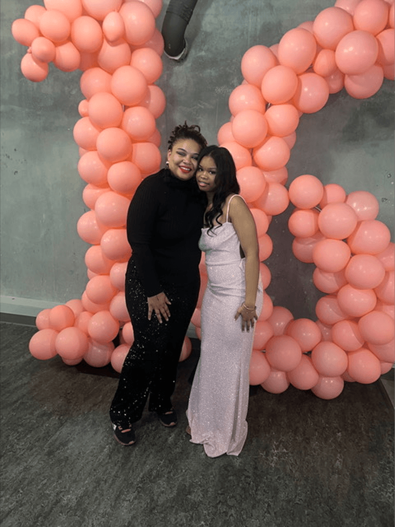 Photo of two women standing in front of pink balloons