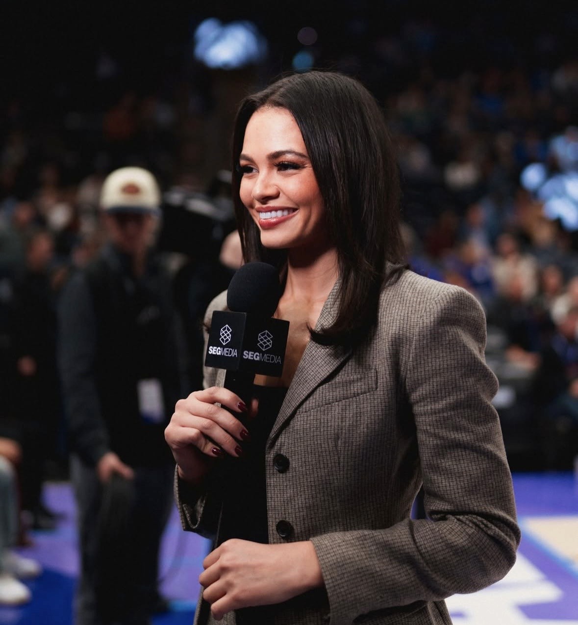 Lauren Green sports reporter holds a microphone and stands on a basketball court, with blurred audience and crew visible in the background.