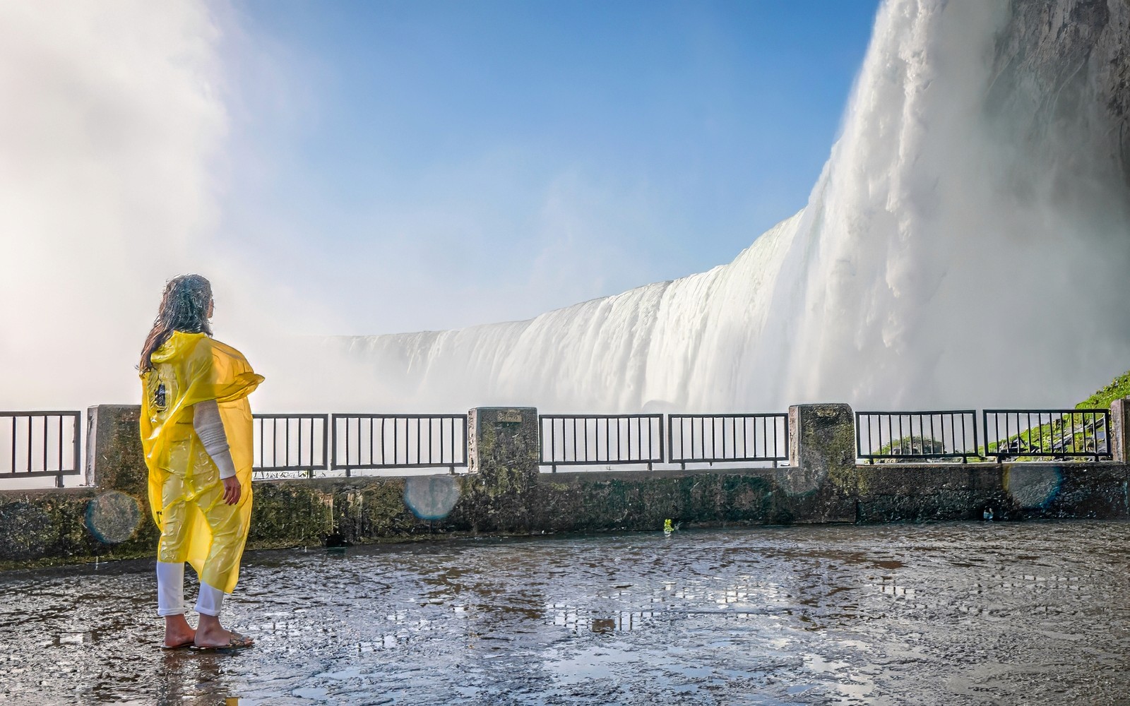 Person in yellow poncho viewing Niagara Falls from observation deck.