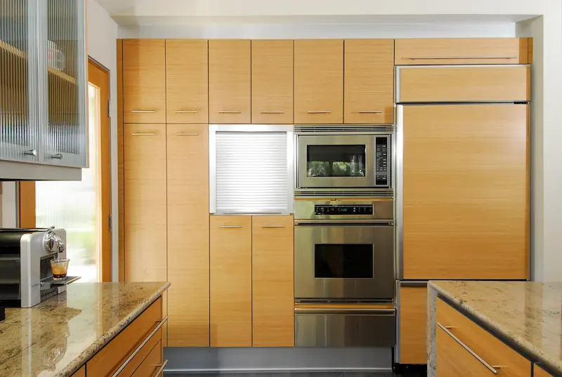 Modern kitchen with wooden cabinetry, stainless steel appliances, and granite countertops. Irvine Transitional Modern. Photo by Chris Darnall.