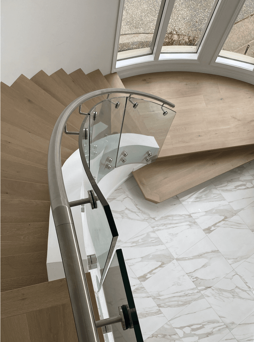 Custom curved glass railing on a spiral staircase with skylight above