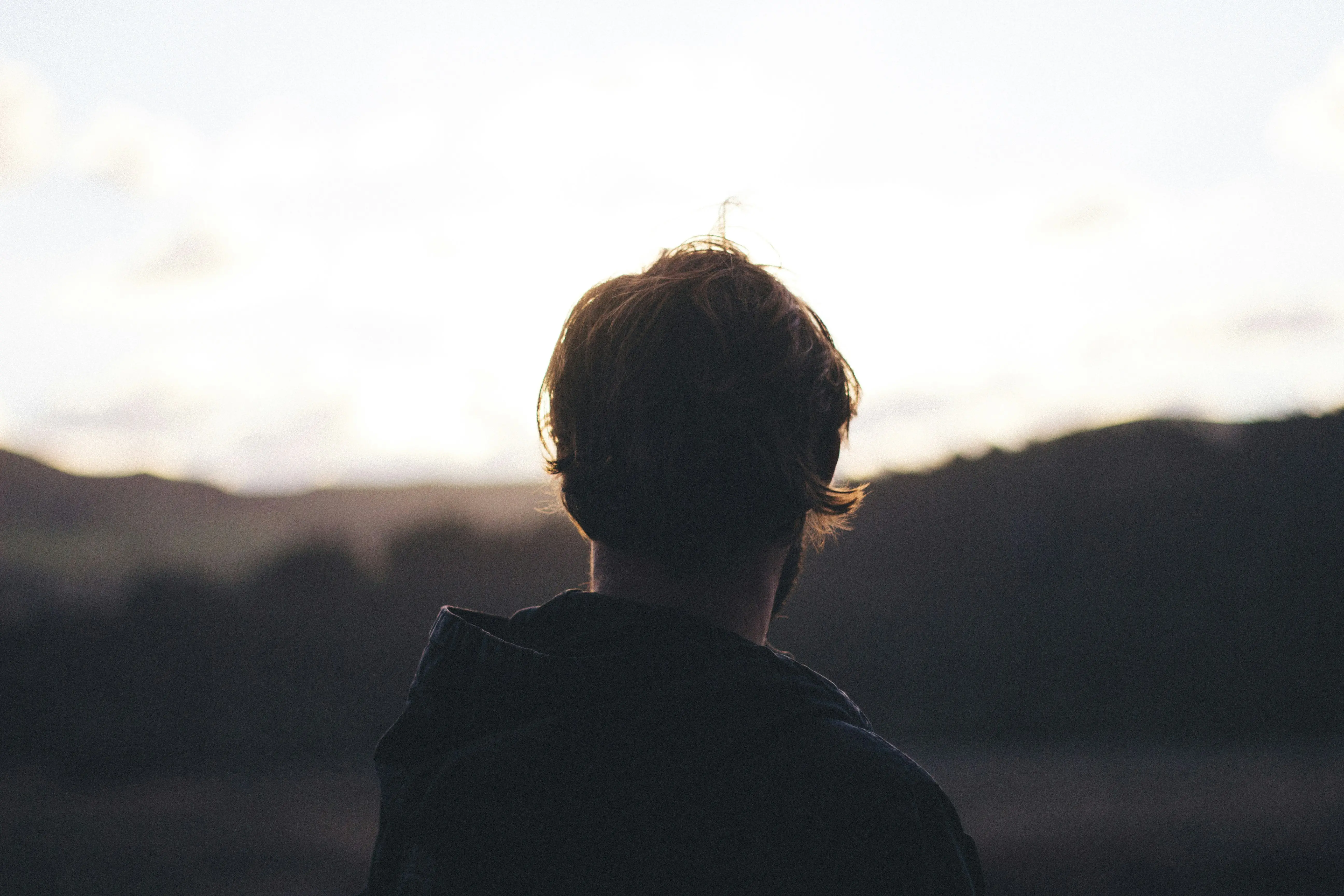 Personne réfléchissant à son avenir professionnel devant un paysage au coucher du soleil