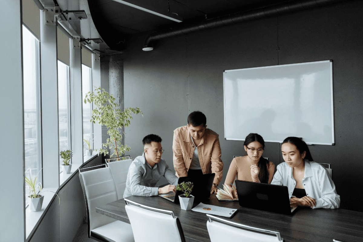 People sitting and working on laptops in a large office.