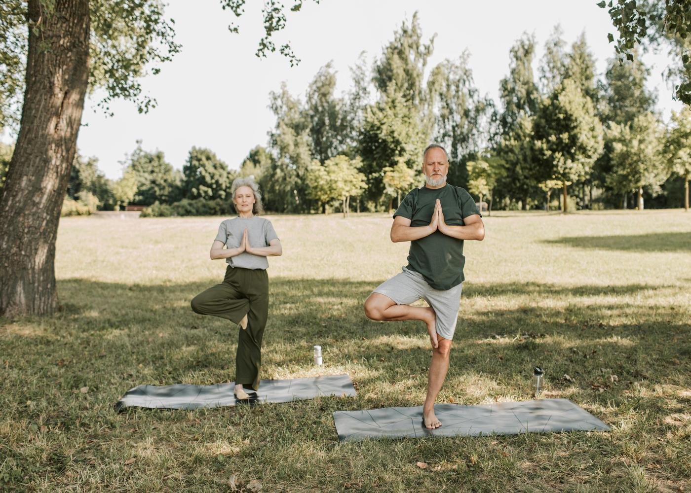 Future of biohacking: elderly man and woman doing yoga under a tree