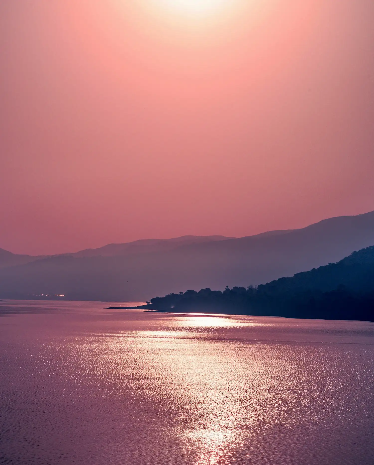 Tranquil sunset over a calm lake with soft pink and purple tones, symbolizing inner peace, mindfulness, and the spiritual journey of healing.