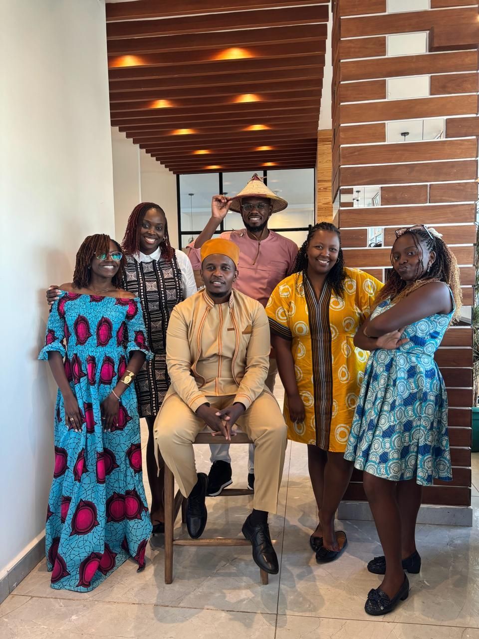 Six Woodrow colleagues posing indoors in bright patterned clothing, celebrating the agency’s campaigning, influence and media work across Africa.