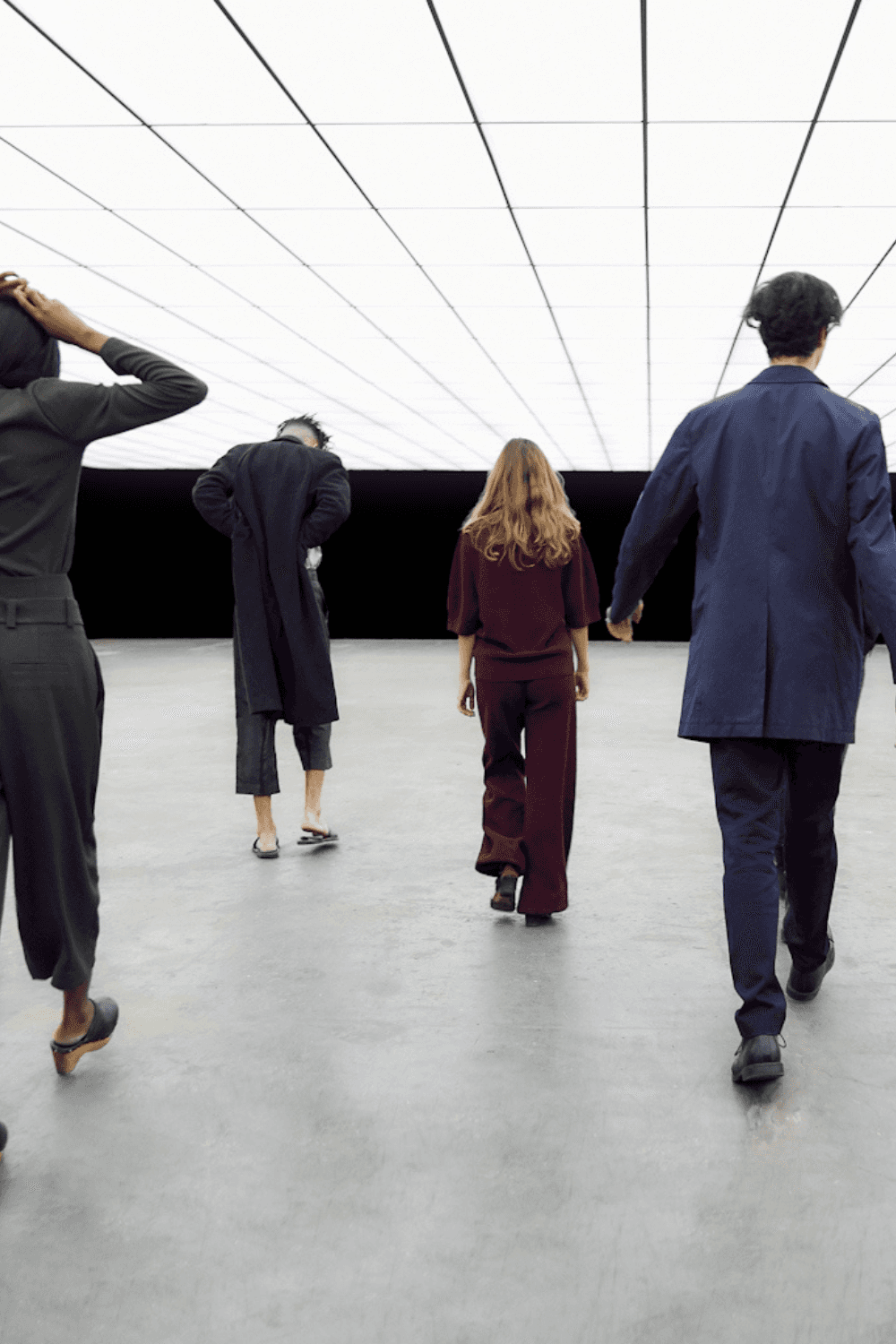 Person in a dark shirton a phone call, seated at a desk with papers, exudes a thoughtful, focused demeanor. Background shows dark horizontal blinds.