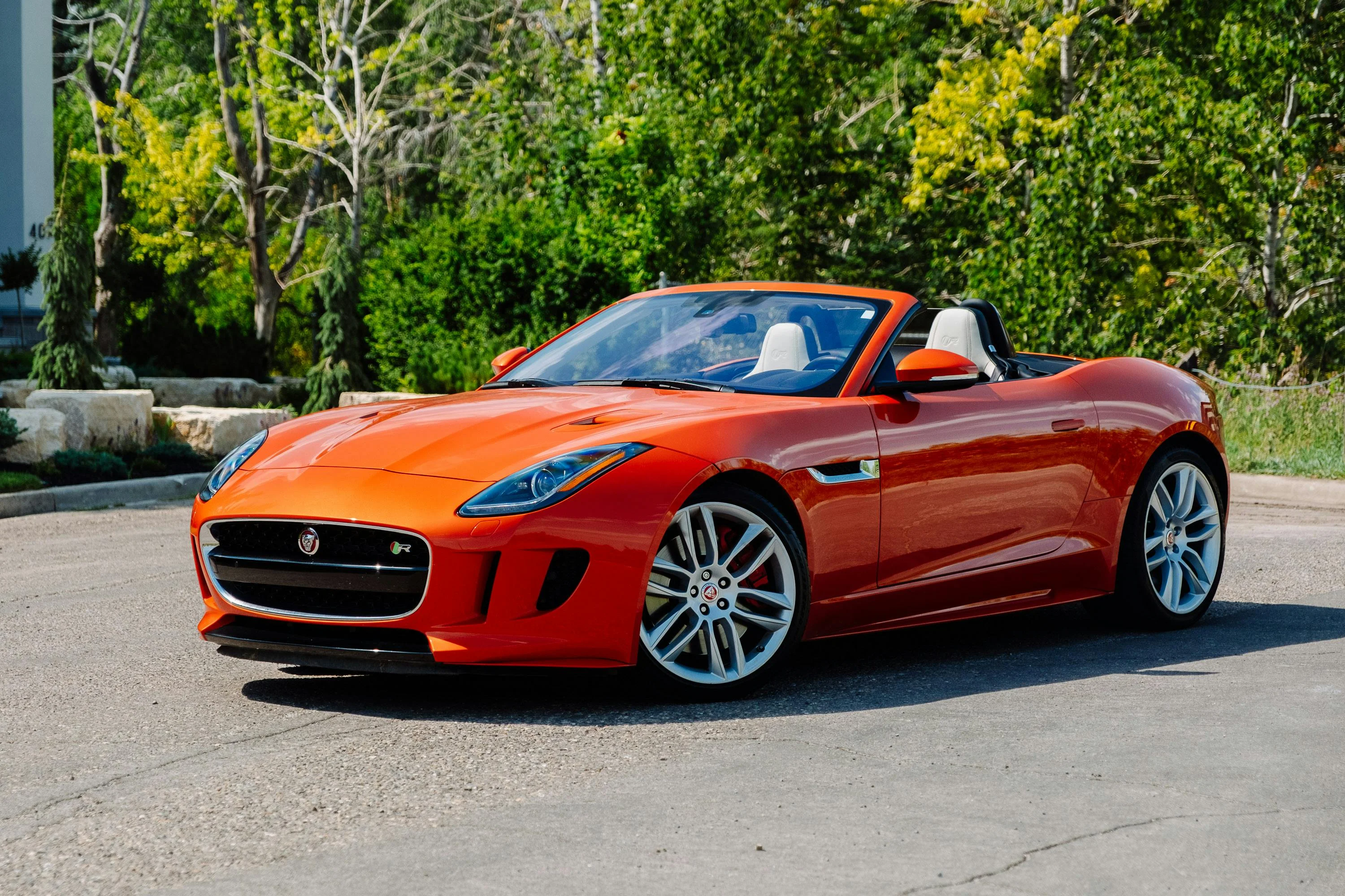 Jaguar F-Type cabriolet orange photographiée en extérieur, dévoilant sa silhouette sportive, ses lignes tendues et sa calandre agressive. Le contraste entre la peinture éclatante, les jantes aluminium et le décor naturel met en avant l’élégance et la puissance de cette sportive britannique.