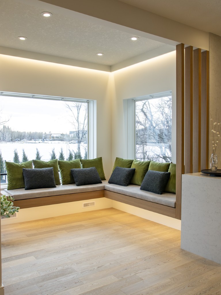 Image of Cozy seating area with green pillows and large windows overlooking a snowy landscape by KHD Homes.