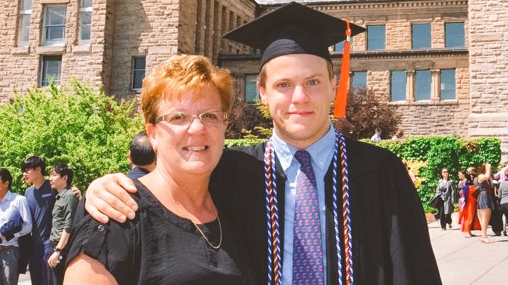 Adam Wolford in cap and gown at Cornell Commencement with his mother