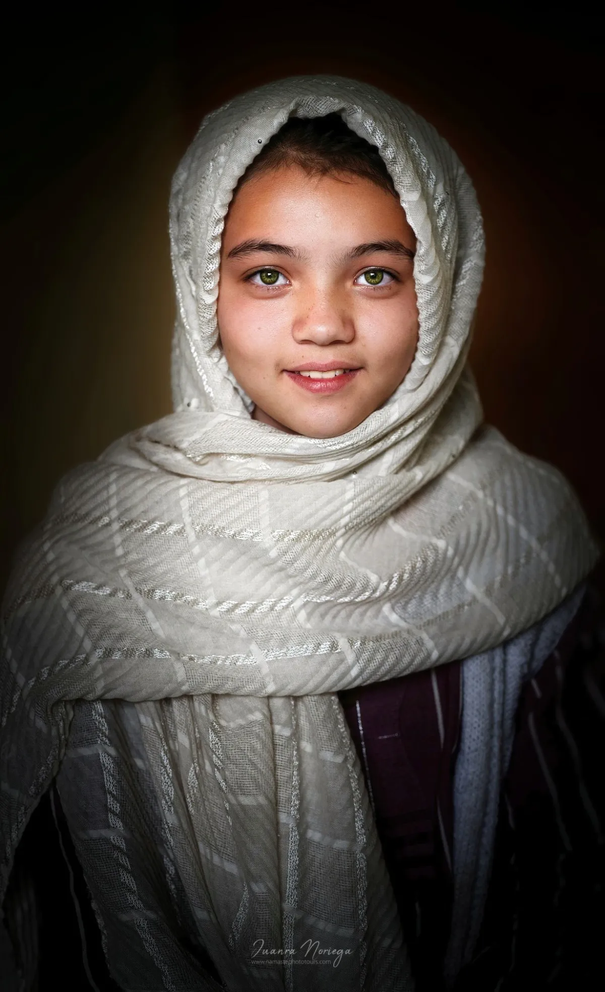Niña sonriente envuelta en un pañuelo blanco, en Ladakh