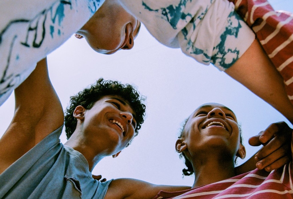 Diverse group of laughing friends huddled together outdoors.