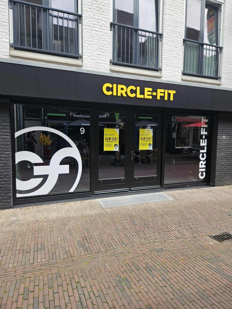 Image of a hub with large windows featuring signage and a prominent logo of Circle Fit, located in an urban area.