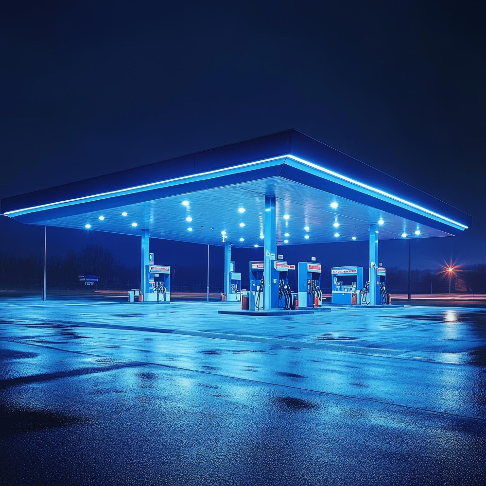 Fuel station operator monitoring digital systems and transactions at a petrol station.