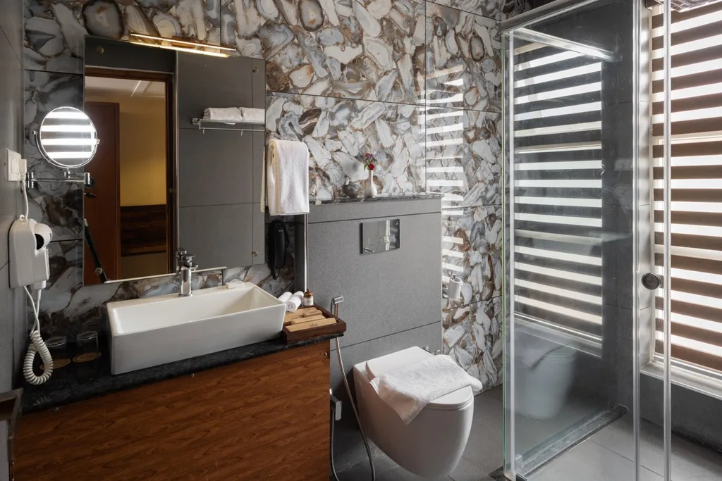 Deluxe Cluster Rooms Bathroom at Au Revoir Wellness Resort – Elegant Design with Modern Fixtures and a Glass-Enclosed Shower