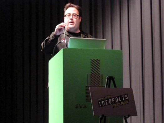 a man is talking at a green stand