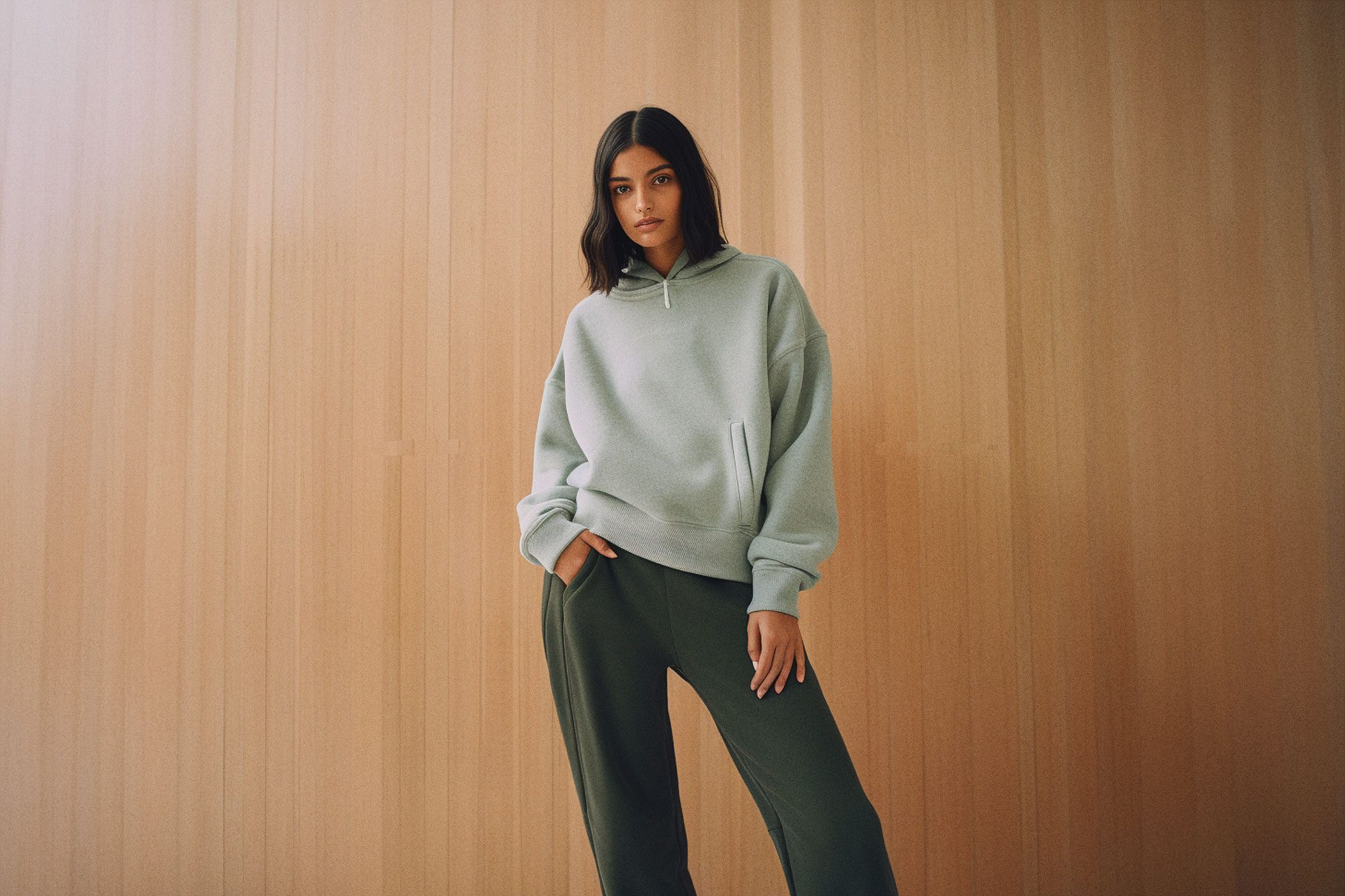 Woman in crewneck standing against wood wall