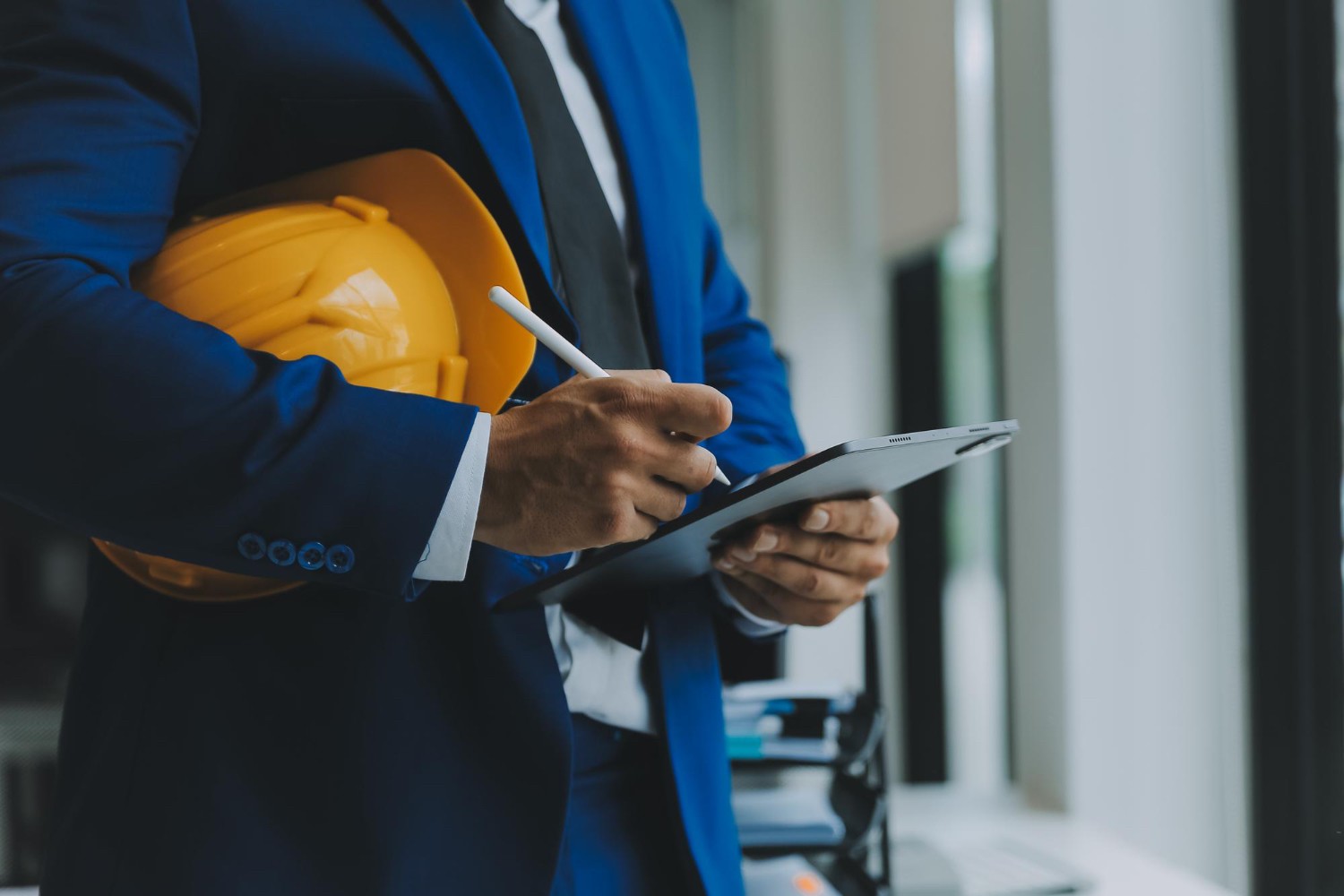 Worker wearing safety gear and checking compliance data on a digital device.
