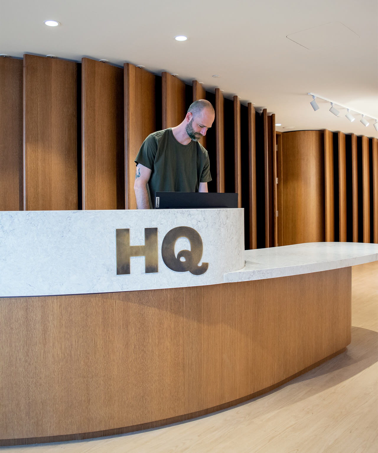 An receptionist standing behind the HQ front desk.