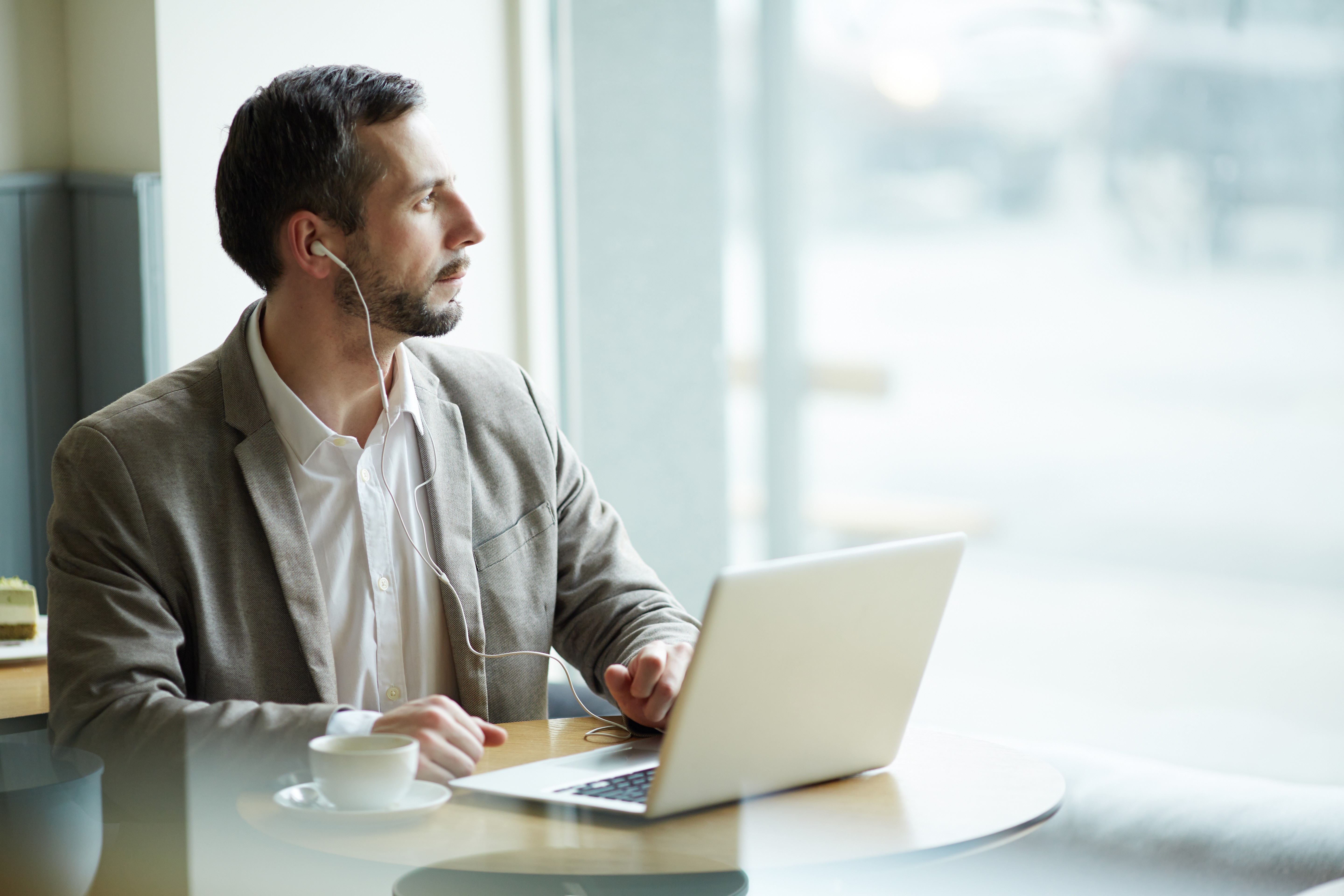 Experienced property investor working on laptop at cafe managing a time-sensitive bridging finance transaction