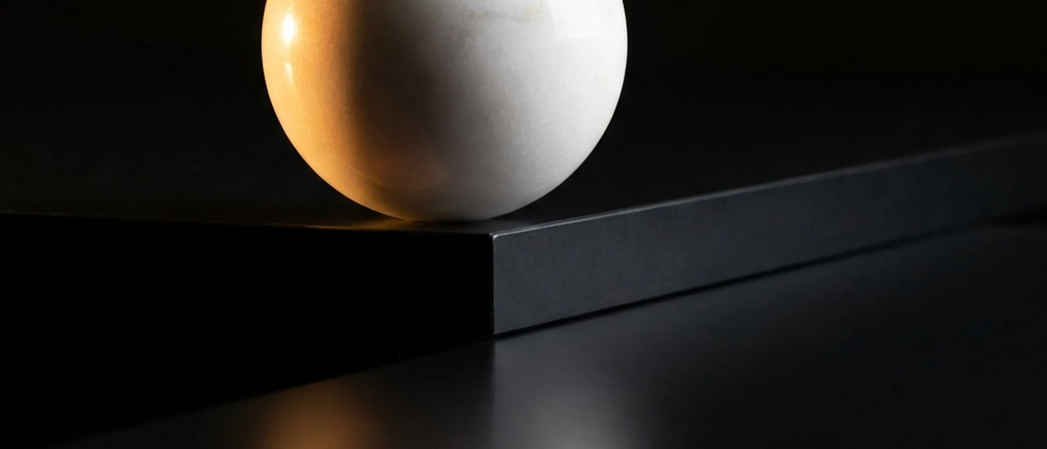 White sphere on a dark surface.