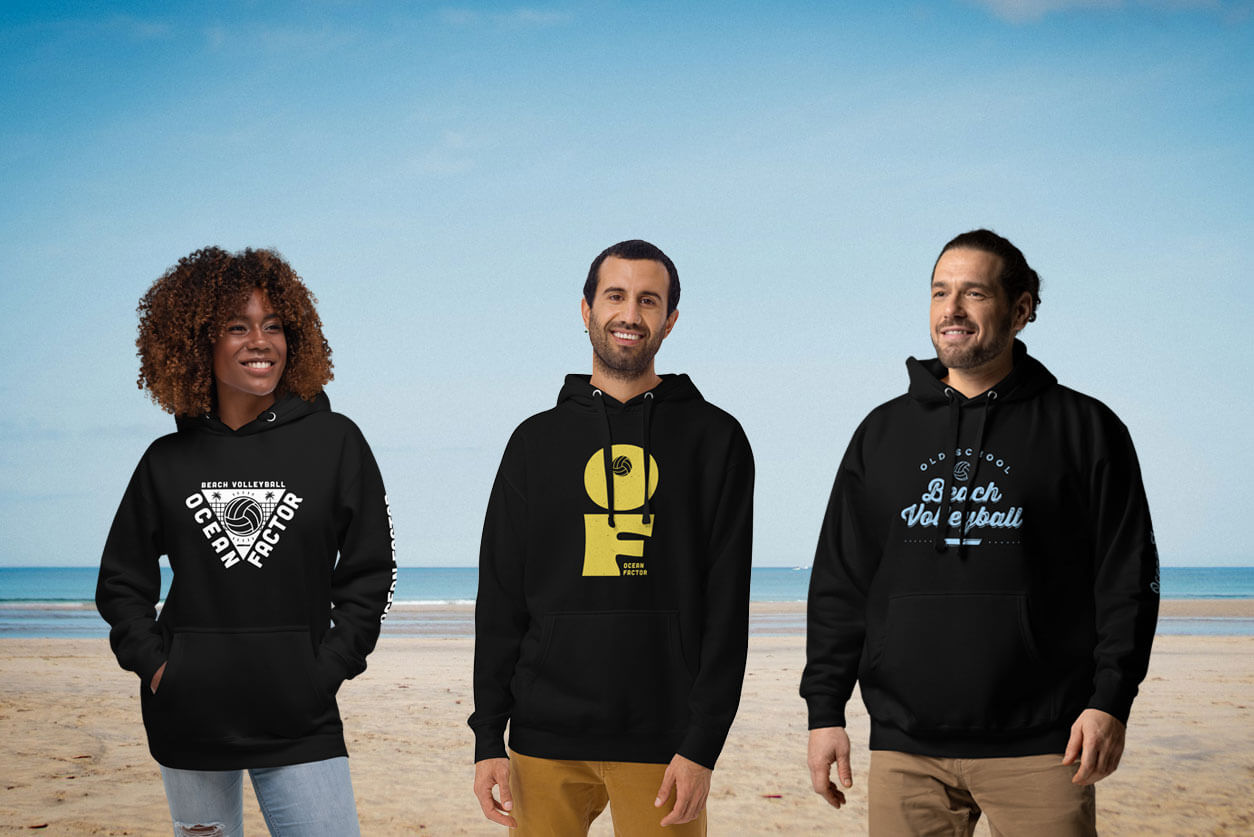 a woman and two men wearing hoodies on the beach