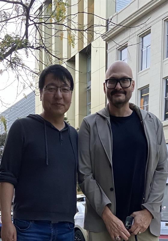a man with his arms crossed standing in front of a desk