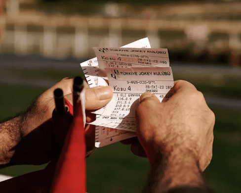  A sports bettor looks at his ticket while betting with friends.