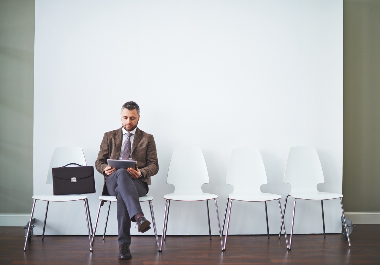 A businessman sitting in a row of chairs, reviewing documents, representing SAA Law's expertise in employment law and workplace legal matters.