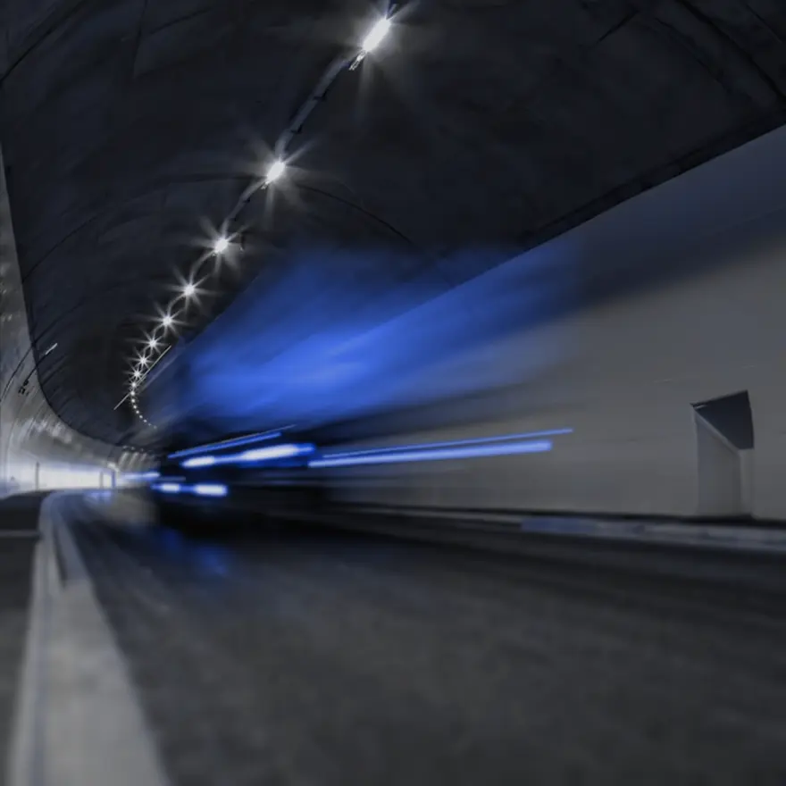 A dimly lit tunnel with blue and white lights, showcasing motion blur from a moving vehicle.