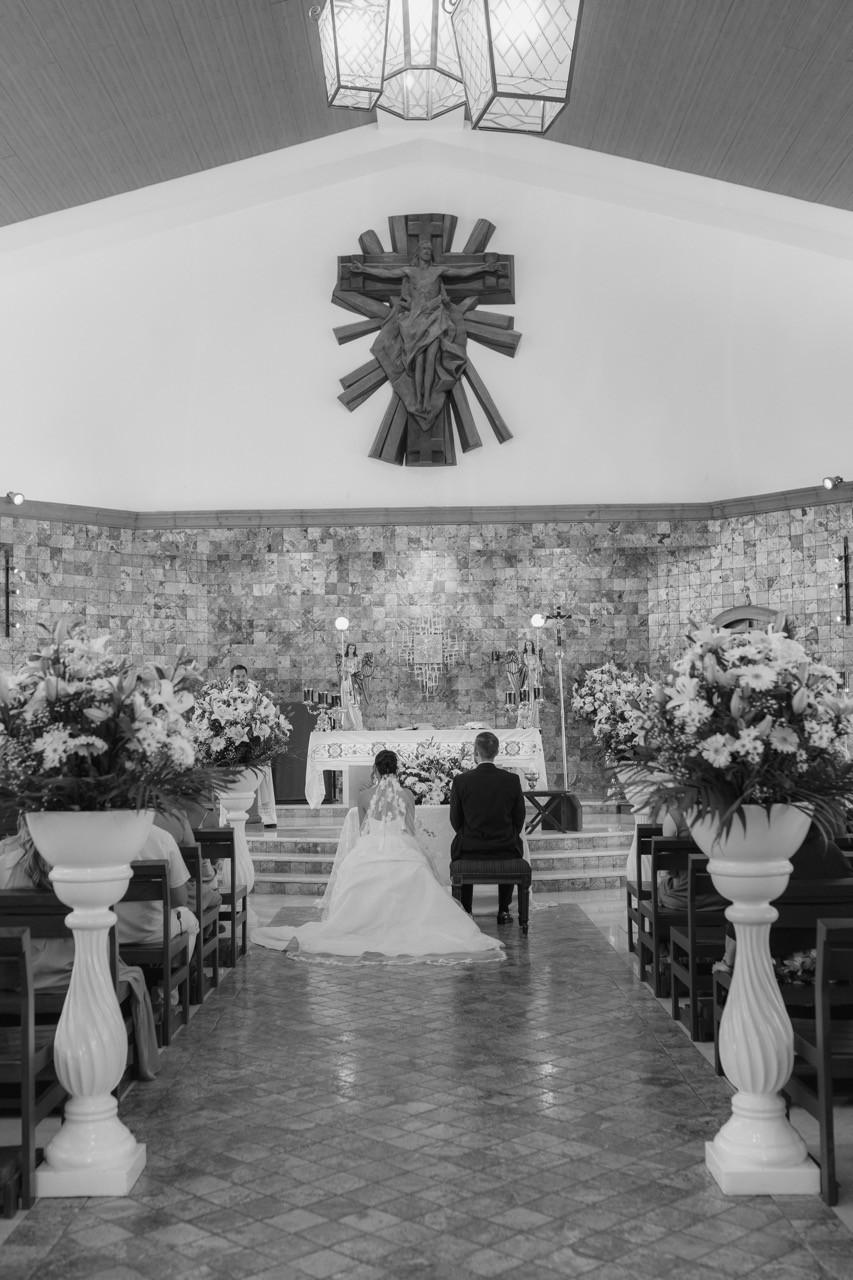 Los novios en una pista de baile a cuadros blancos y negros, con instalaciones florales colgantes en una recepción de boda junto al lago