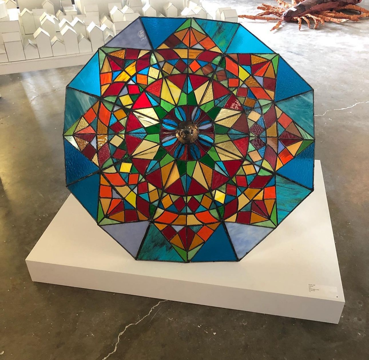 Image of my stained glass umbrella sculpture with a kaleidescope effect, featuring hundreds of triangular, multi-colored glass pieces arranged in a vibrant, intricate pattern.