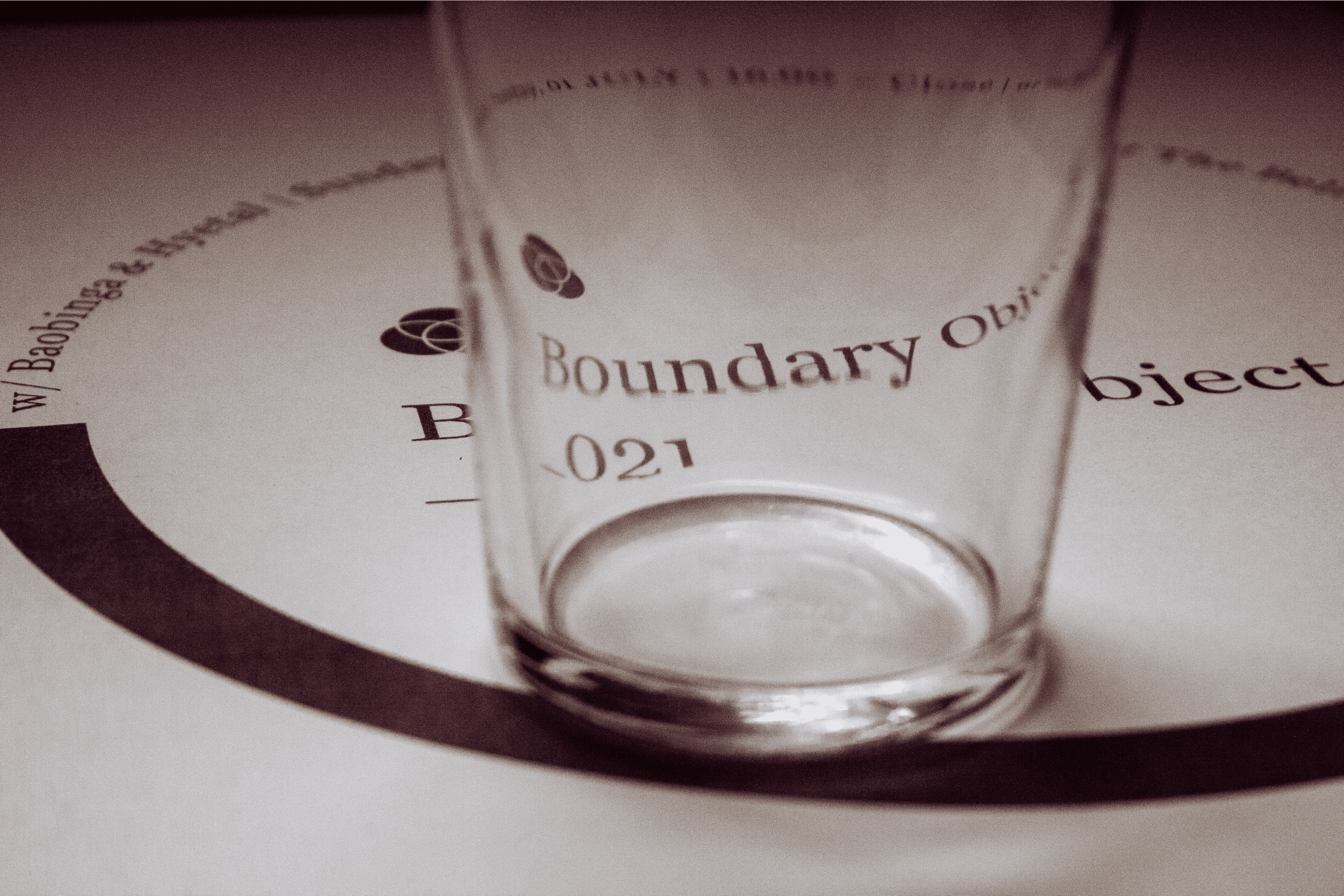 Boundary Object music event poster distorted while being viewed through an empty pint glass