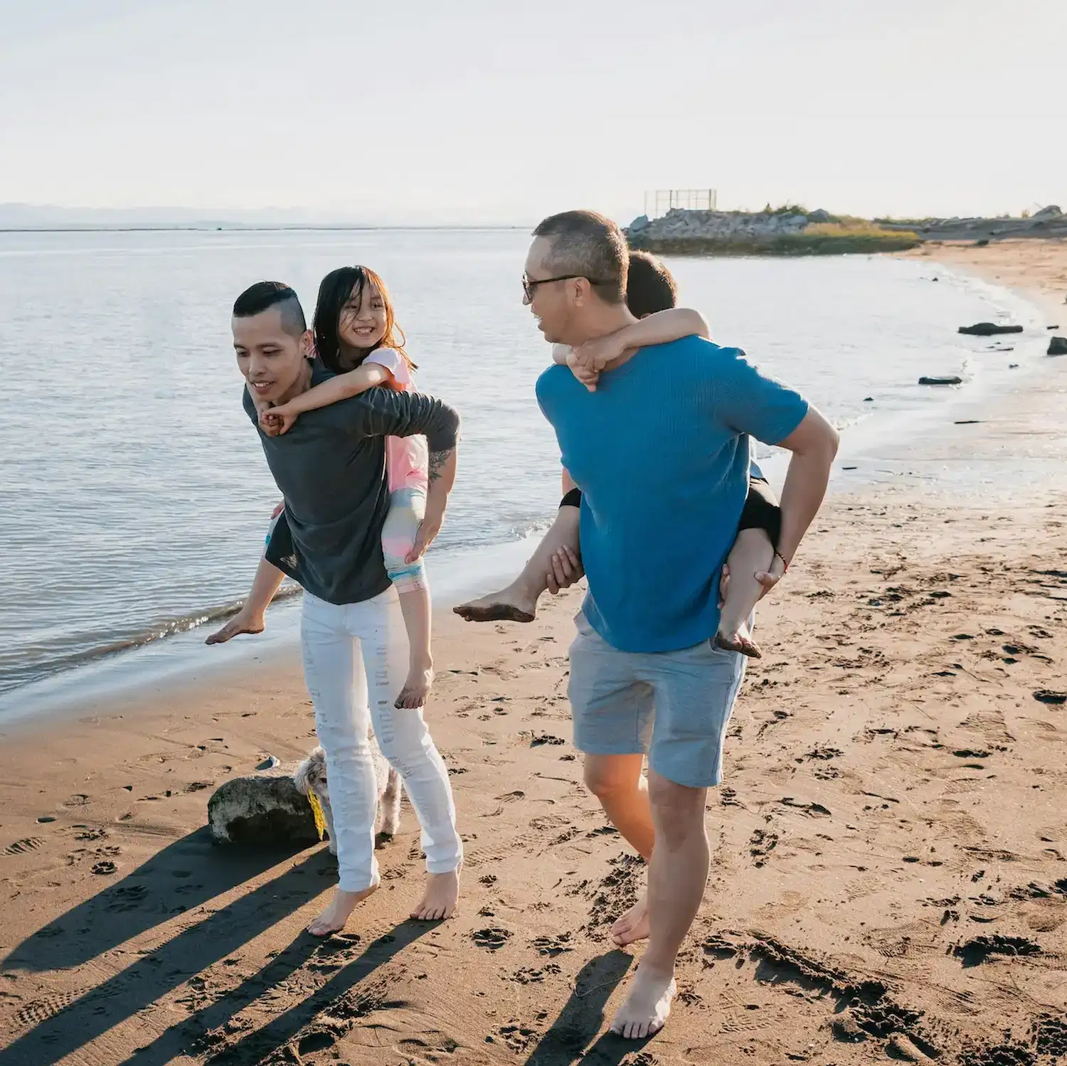 LGBTQ+ family walking together along the beach, representing love, connection, and inclusive family therapy for queer parents and children in New York City.