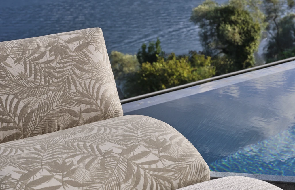 Modern outdoor (مجموعة أثاث متكاملة) furniture scene with curved wooden armchairs in solid Iroko and upholstered cushions, arranged poolside next to tropical greenery – contemporary luxury collection for stylish open-air living spaces