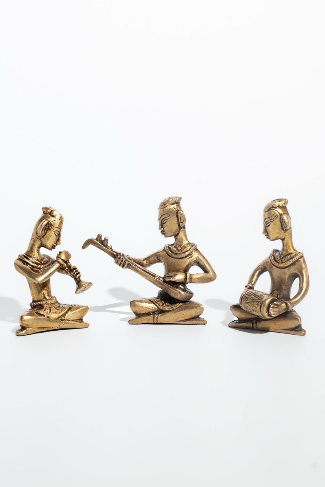 Three brass figurines of musicians on a white background