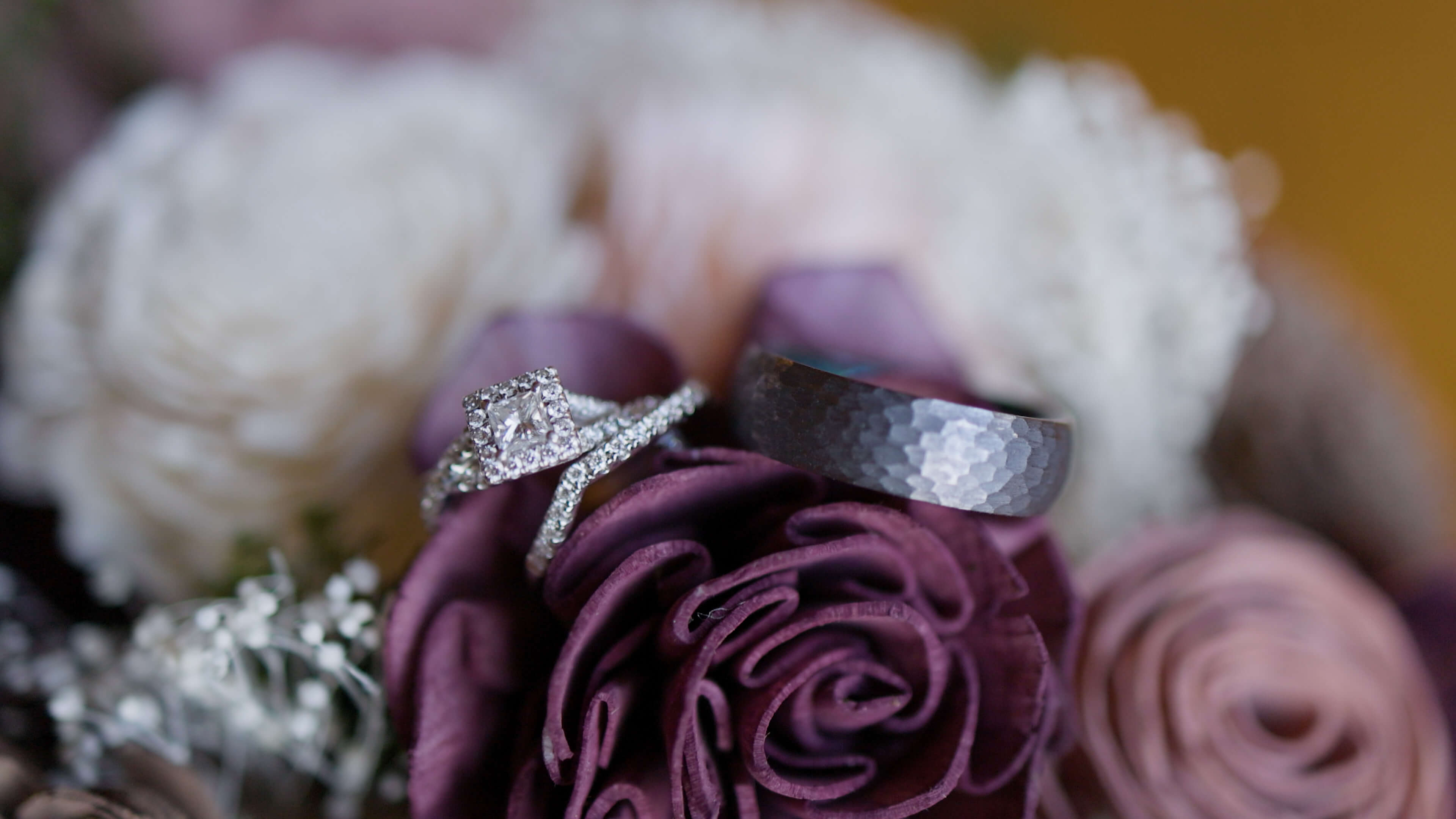 Two wedding rings sitting on top of a bouquet of flowers
