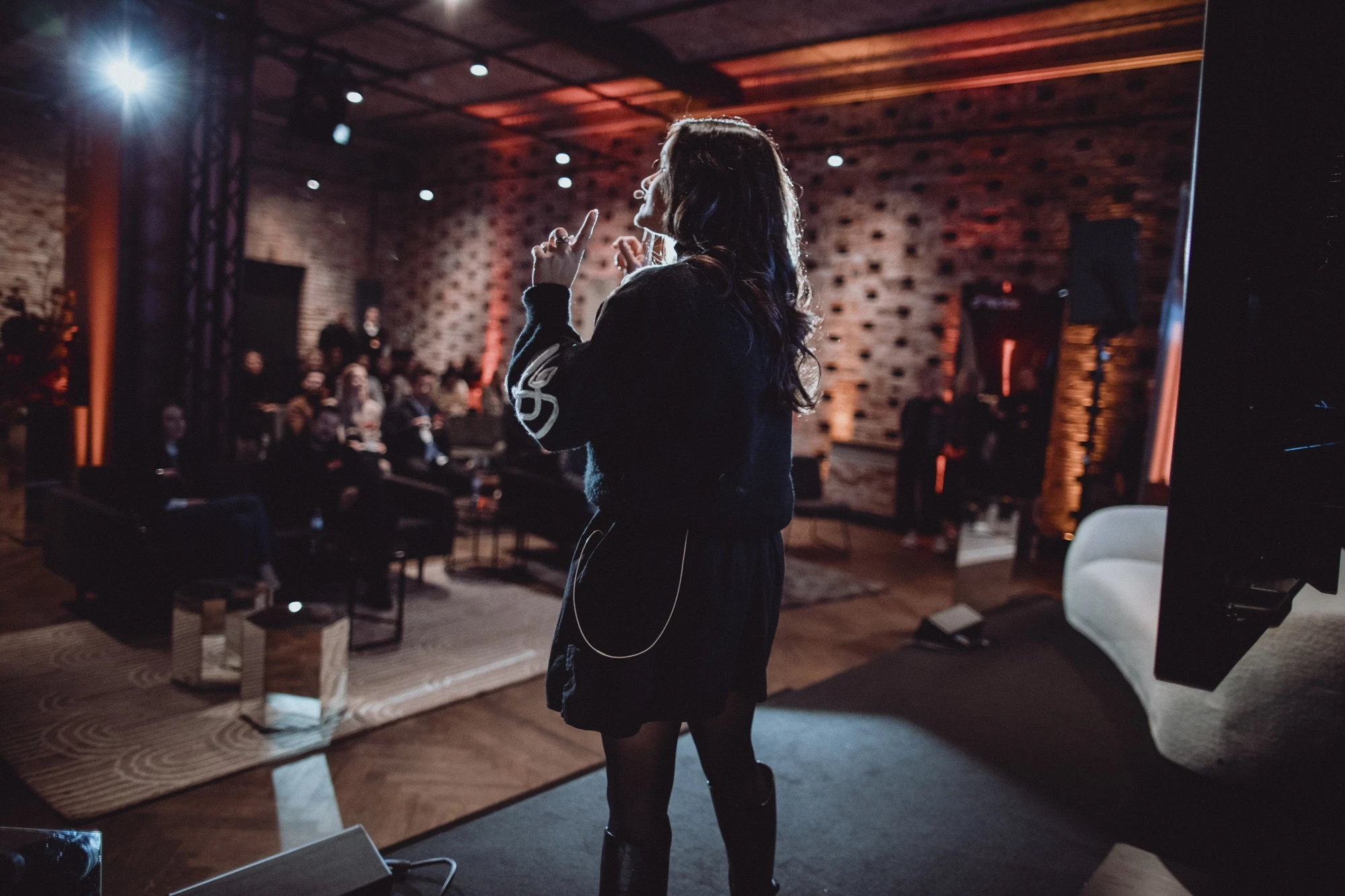 Speaker on stage in front of the audience in the warm-lit loft at the TikTok Summit.
