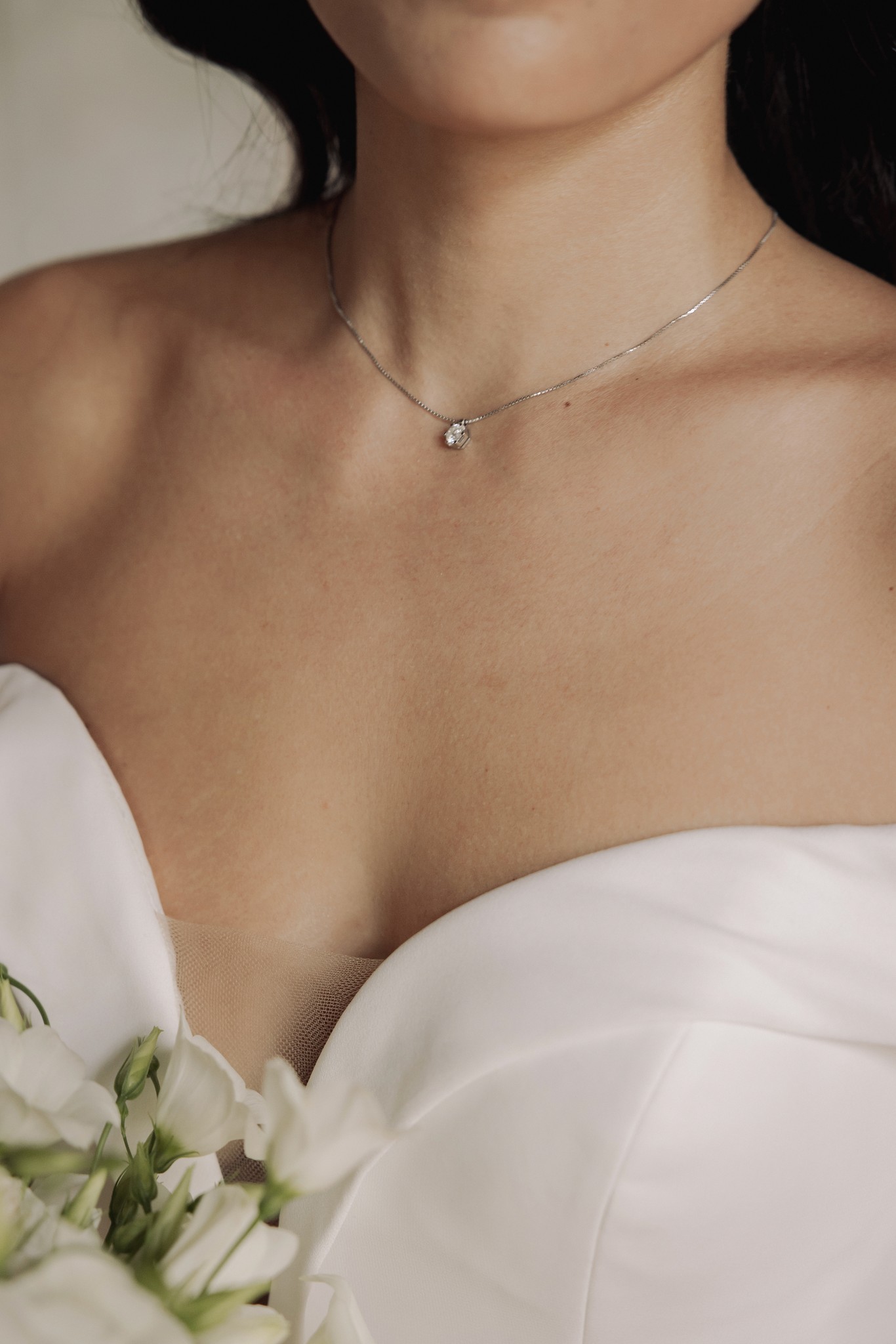 Sposa con abito bianco e collana d'argento, dettaglio del busto con bouquet bianco, reportage matrimoniale a Villa Negri