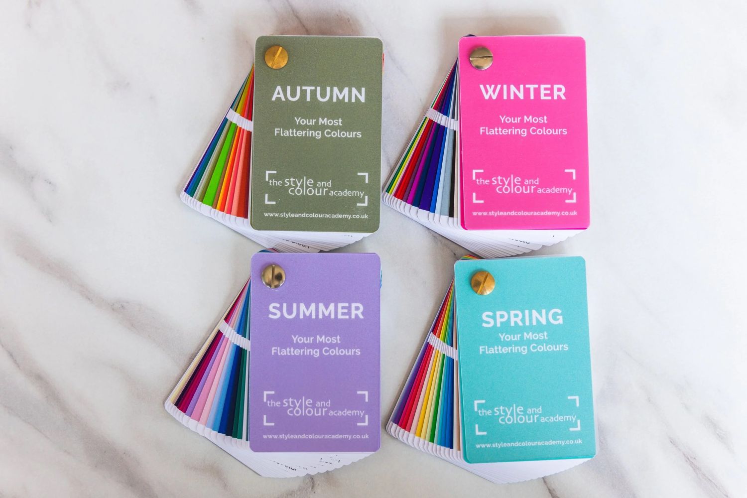 Four seasonal colour fan decks labeled Spring, Summer, Autumn, and Winter, each showing a range of fabric swatches used in personal colour analysis to identify the most flattering tones.