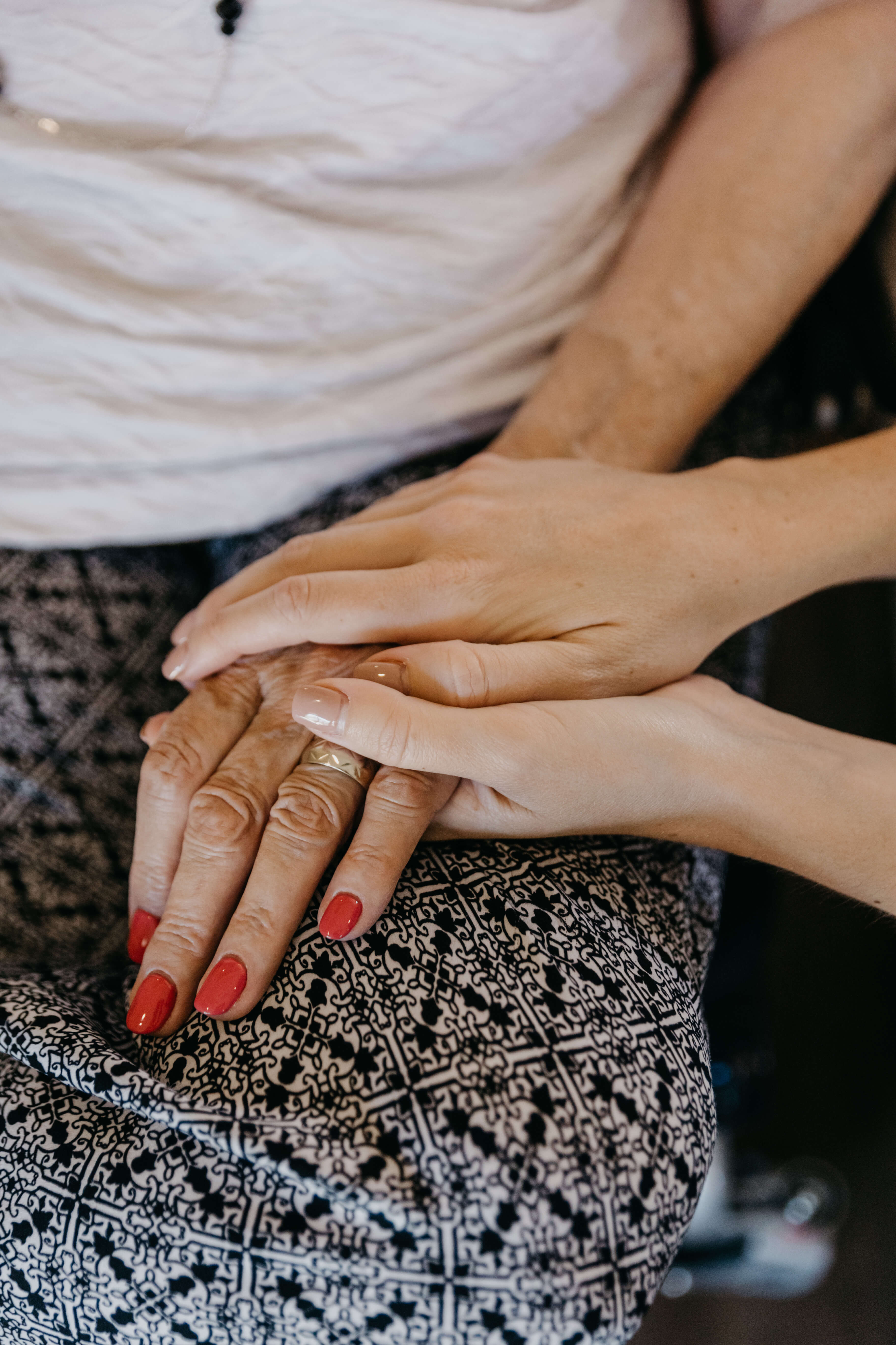 Close up image of caregiver's hands comforting their client.