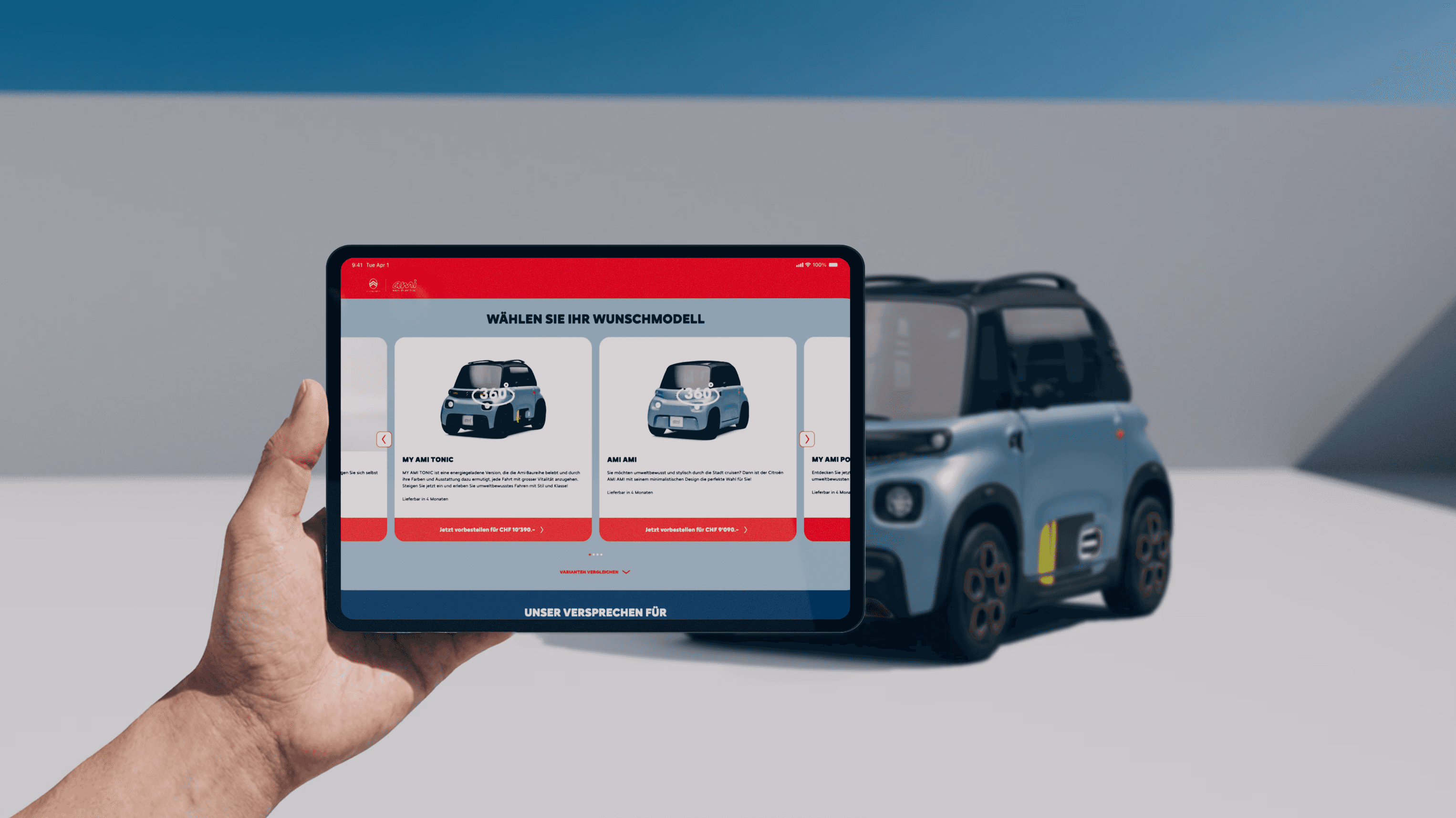 Eine Hand hält ein Tablet im Querformat, auf dem der Citroën-Shop in der Schweiz angezeigt wird. Hinter dem Automodell.