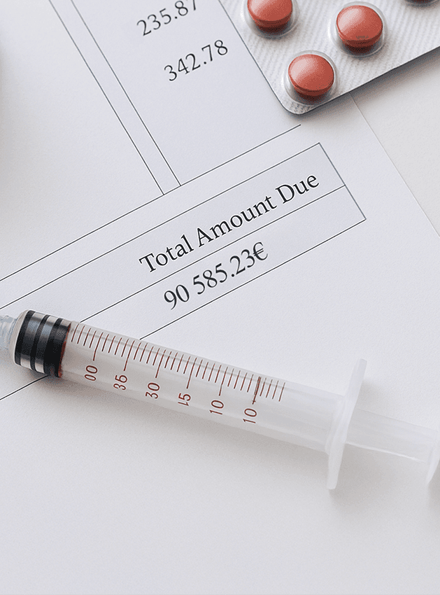 Close-up of hospital financial documents showing high amounts (235.81€, 342.78€, etc.), with medications and a syringe placed on top, symbolizing rising healthcare costs